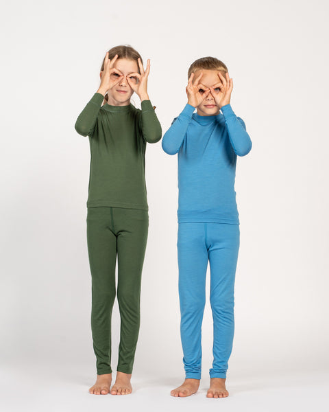 Twee kinderen dragen groene en blauwe pyjamapakjes op een witte achtergrond