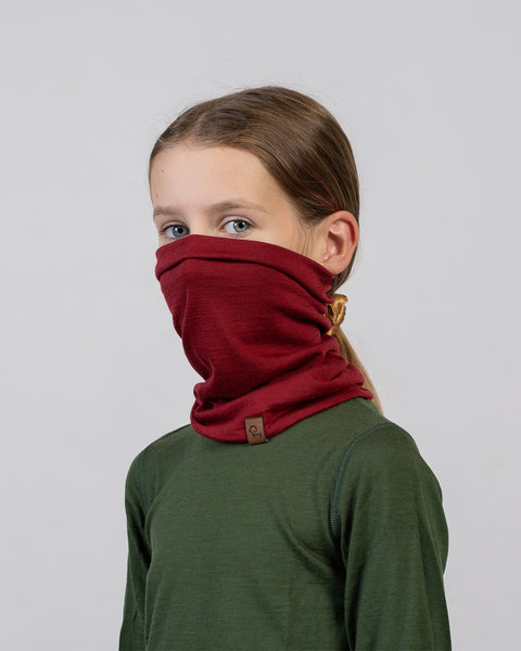 Meisje in een groen shirt met een rode merinowollen nekwarmer – veelzijdige en comfortabele winterkleding voor kinderen.