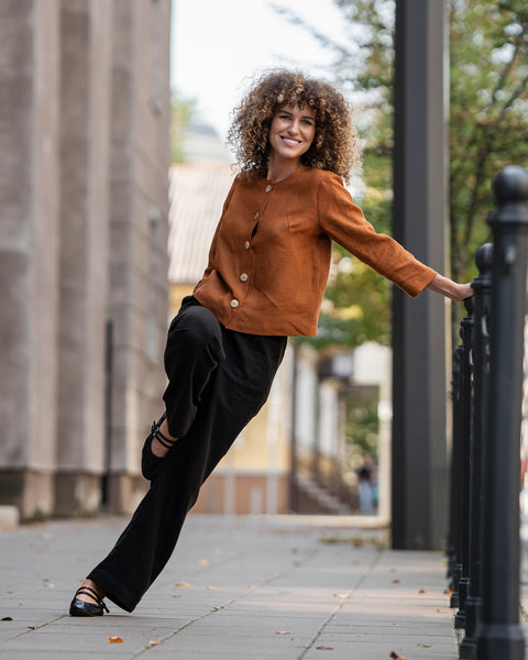 Woman with curly hair wearing almond brown linen jacket Alice and standing in astreet