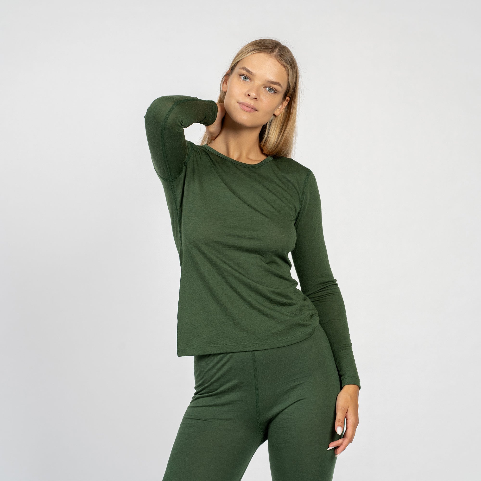 Het donker groene lange mouwen shirt van merinowol voor dames van menique, gecombineerd met donker groene broek van menique, van voren gezien.