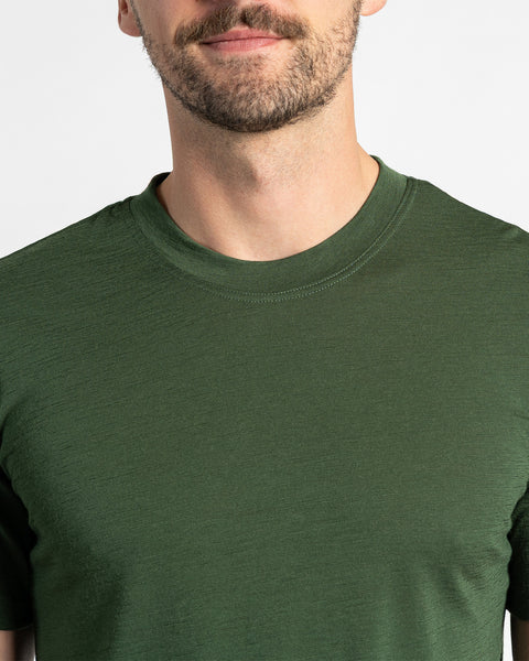 Close-up van een donkergroen Menique T-shirt, met zichtbare merinowolstructuur en een ronde hals.