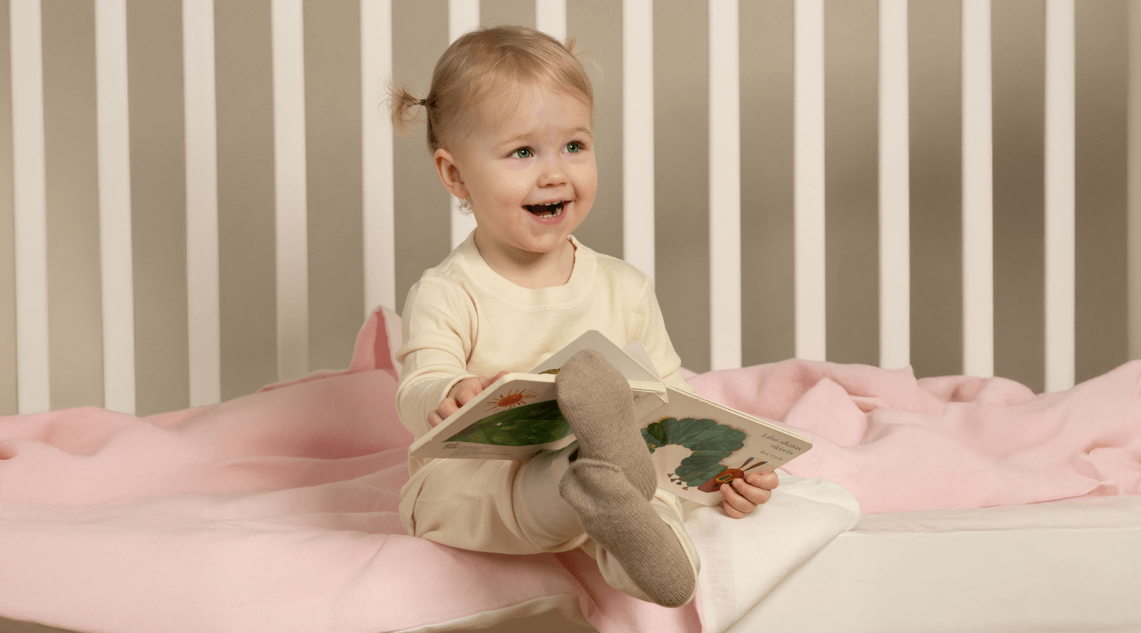a little baby girl wearing a beige two piece set of merino clothing.