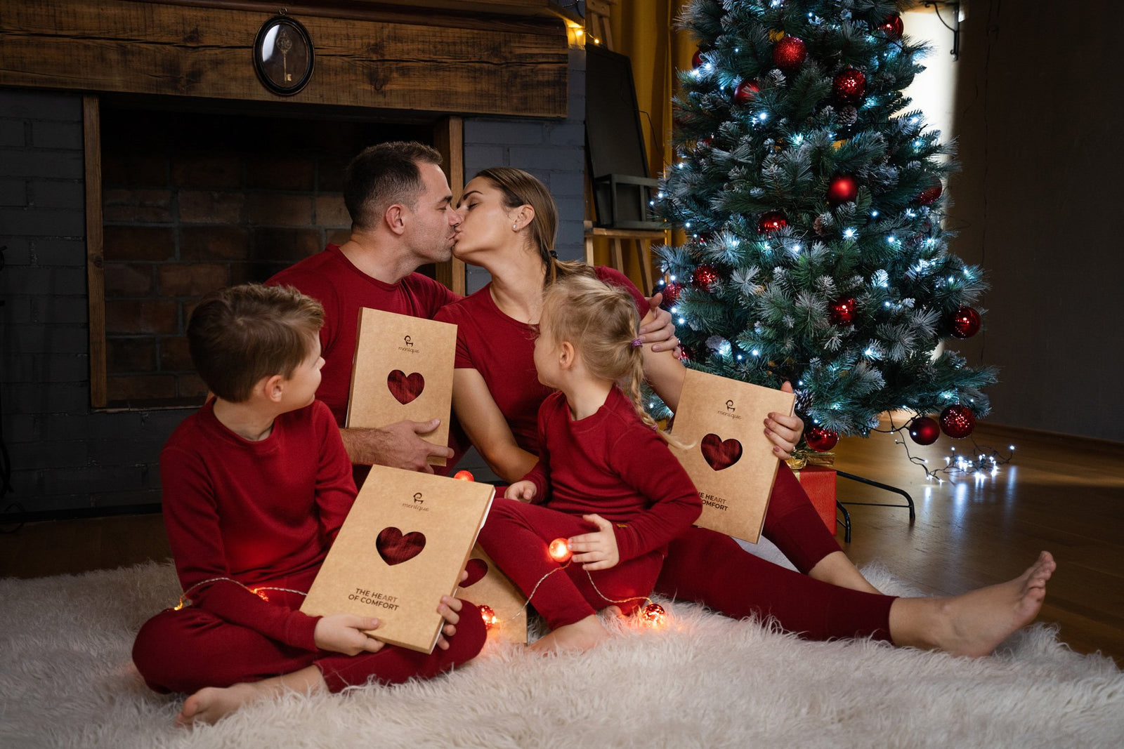 Gelukkig gezin zit bij een kerstboom in bijpassende rode kleding en wisselt cadeaus uit.