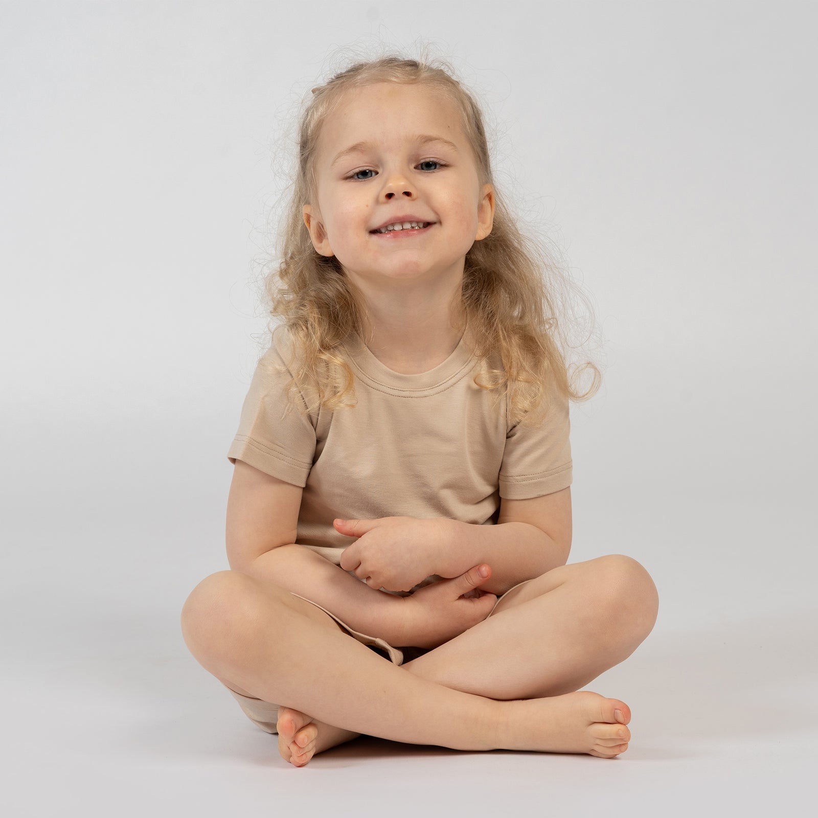 Kids beige bamboo clothing set – girl squatting in soft breathable t-shirt and shorts