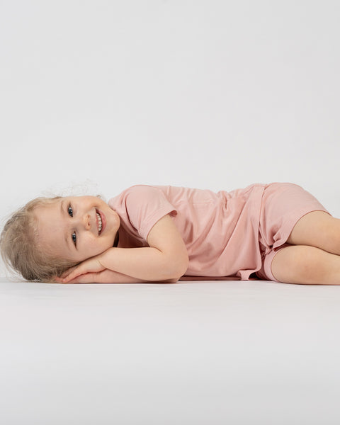 Girl lying down wearing pink bamboo t-shirt and shorts – soft breathable kids loungewear set