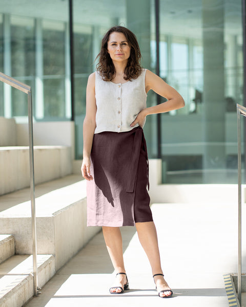 Woman standing on a modern architectural staircase wearing a menique sleeveless top and skirt in the color shadow purple.