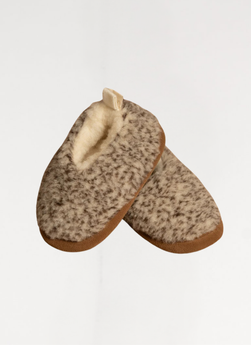 A close-up product shot of two fuzzy, grey-speckled wool slippers featuring brown edging and a plush cream-colored inner lining.