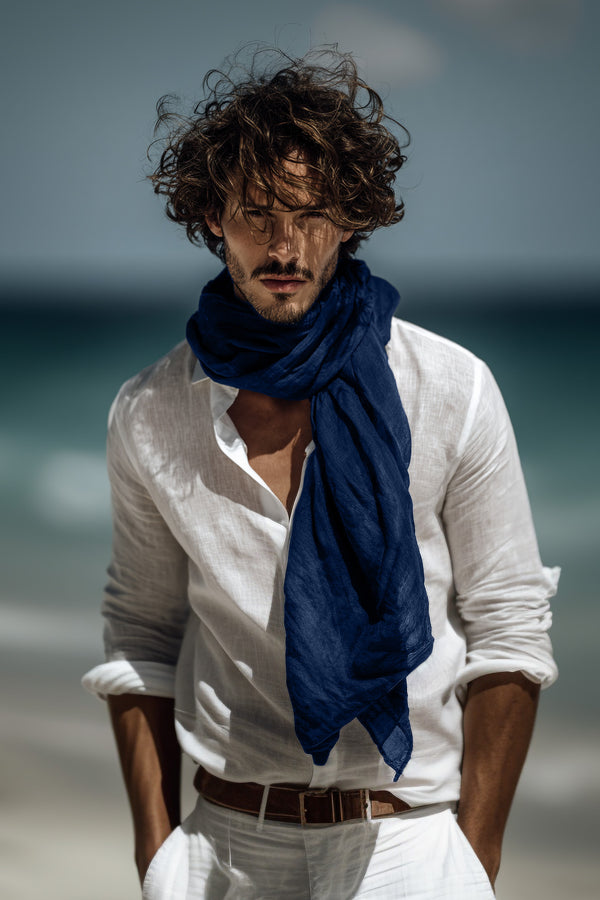 Man wearing a white shirt and blue scarf on a beach