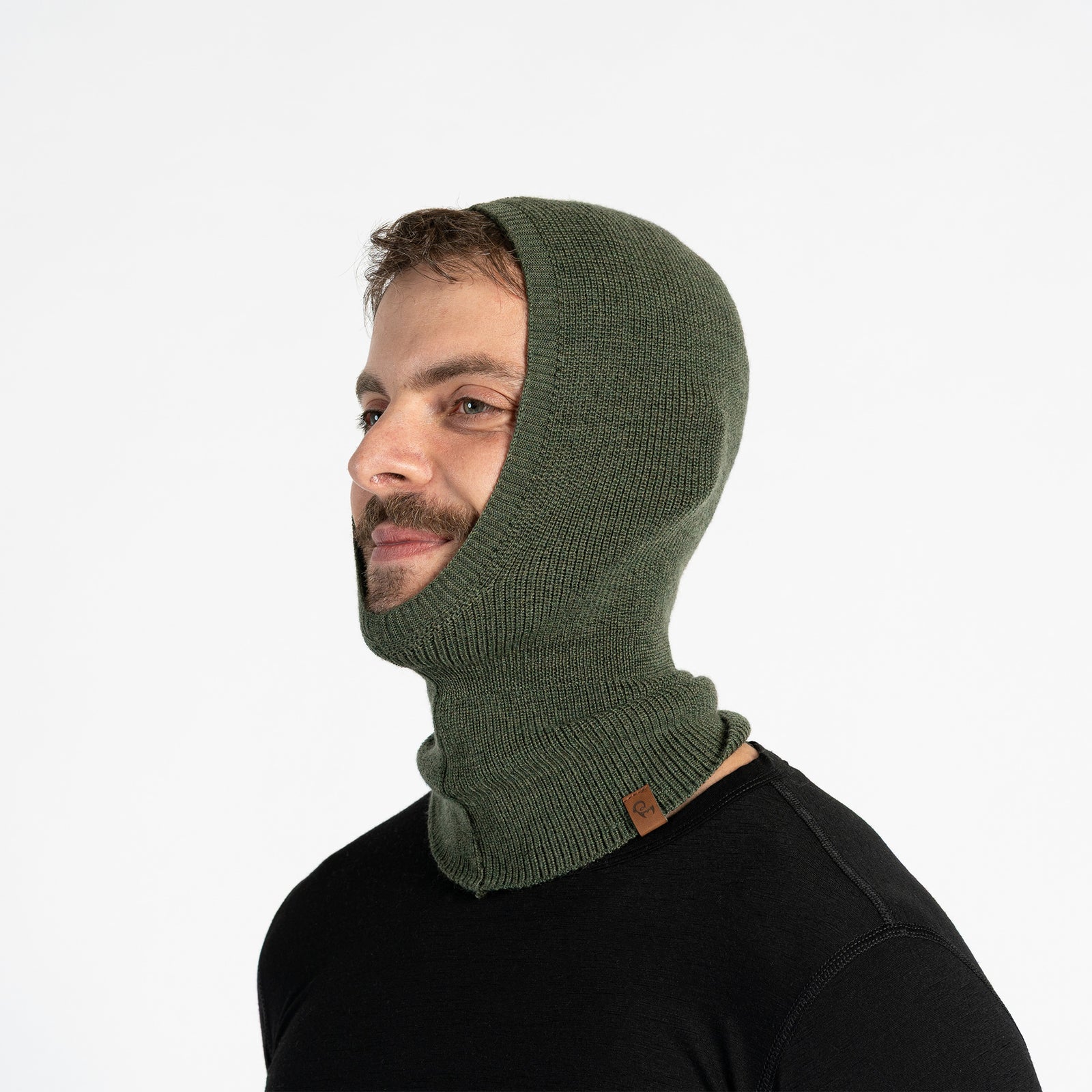 Glimlachende man op de skipistes met een donkergrijze merinowollen binnenbalaclava onder een blauwe skipak en skibril.