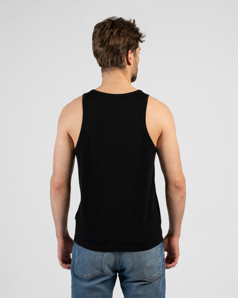 A studio shot showing the back of a man wearing a solid black tank top and medium-wash blue jeans. The background is a plain light grey.