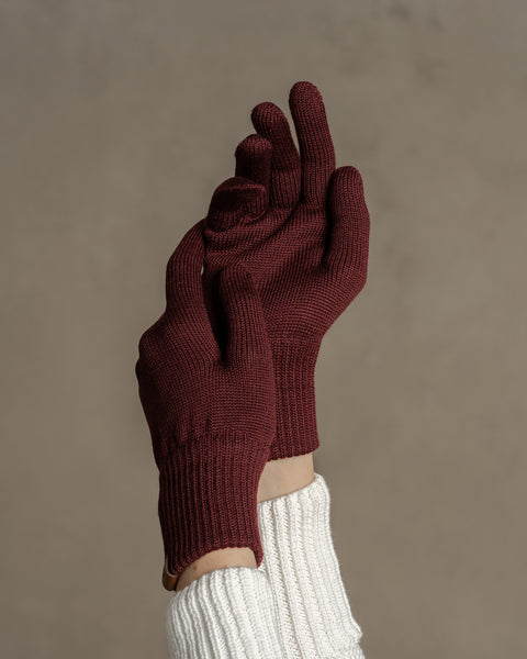 Close-up of royal cherry merino wool knit gloves worn on raised hand, emphasizing smooth knit structure and snug cuff.