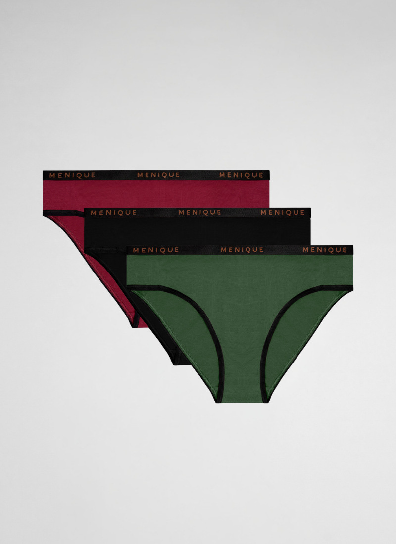 A three-pack of women's bikini underwear in deep red, black, and dark green is arranged diagonally against a light gray background. Each pair features black trim along the leg openings and a matching black elastic waistband displaying the brand name "MENIQUE" in copper lettering.