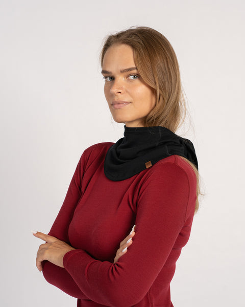 Woman wearing a black Merino wool balaclava pulled down and styled as a neck warmer with arms crossed.