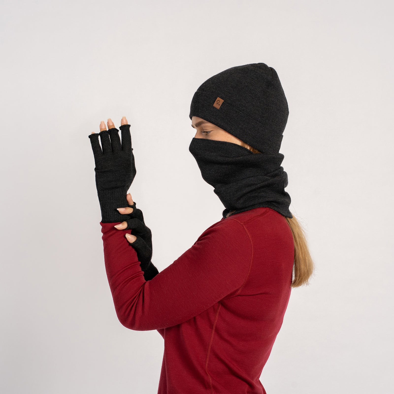 Donkergroene menique gebreide muts, nekwarmer en vingerloze handschoenen set op een witte achtergrond