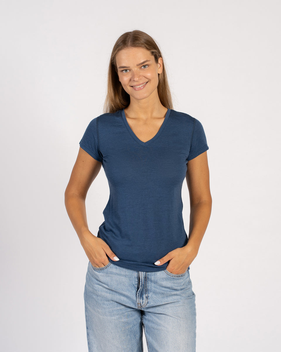 Vrouw die lacht in een denimblauw Merinowollen T-shirt met V-hals en korte mouwen.