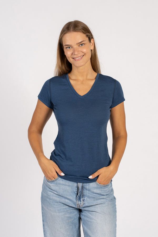 Vrouw die lacht in een denimblauw Merinowollen T-shirt met V-hals en korte mouwen.