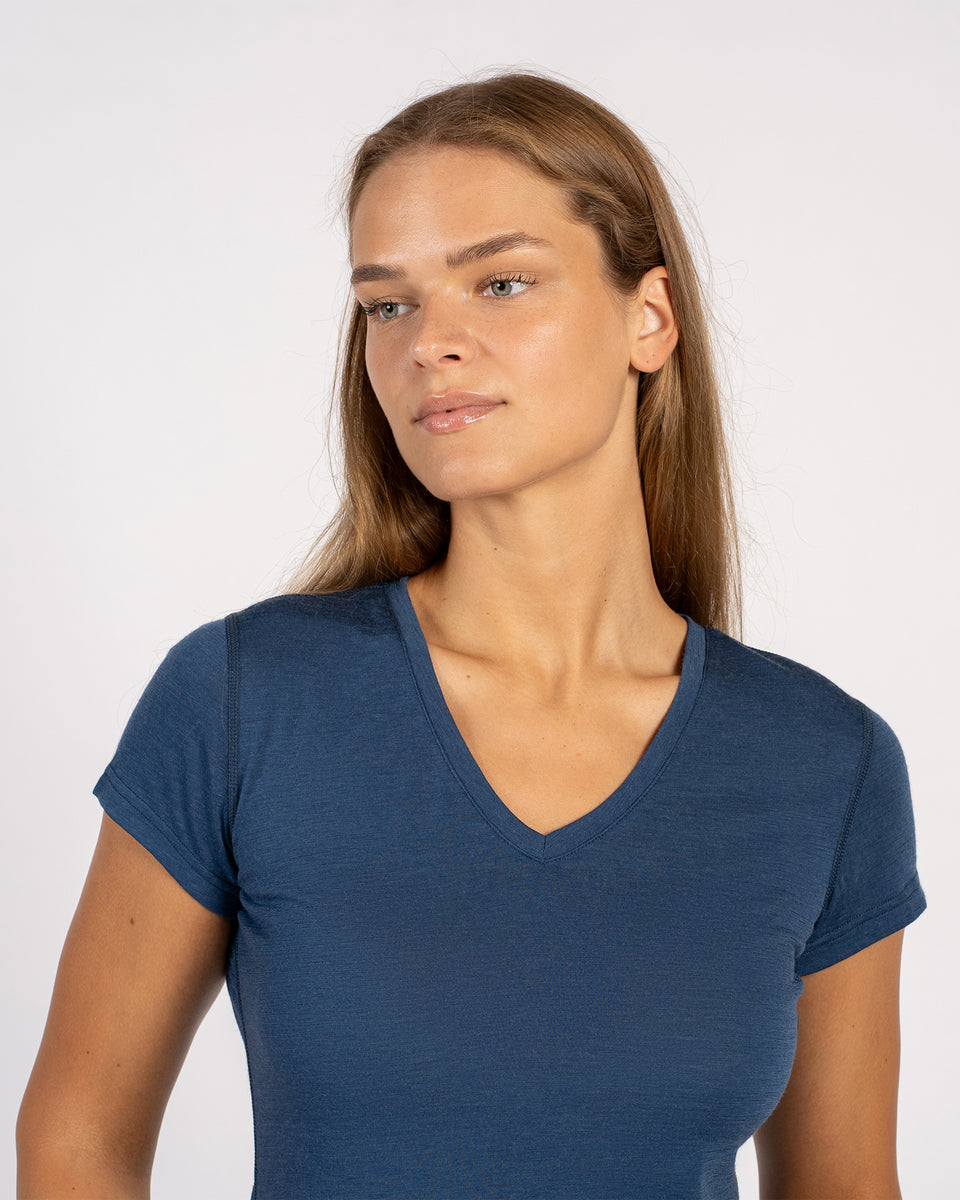 Close-up van een vrouw die een denim Merinowollen T-shirt met V-hals en korte mouwen draagt.