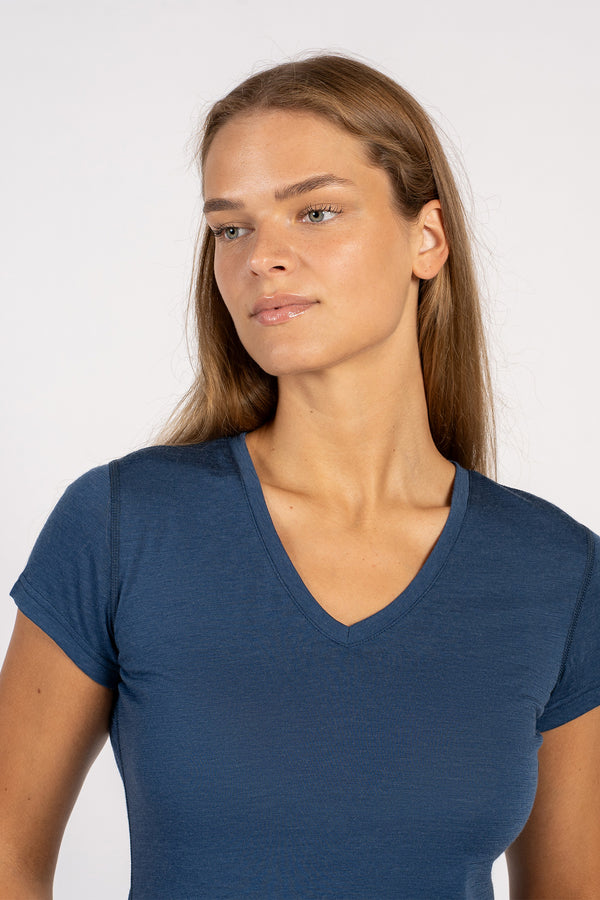 Close-up van een vrouw die een denim Merinowollen T-shirt met V-hals en korte mouwen draagt.