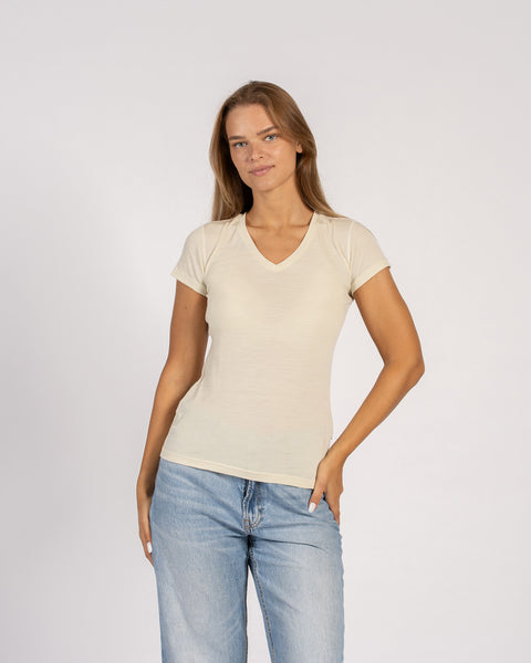Vrouw draagt een T-shirt met V-hals van merinowol in natuurlijke kleur en korte mouwen.
