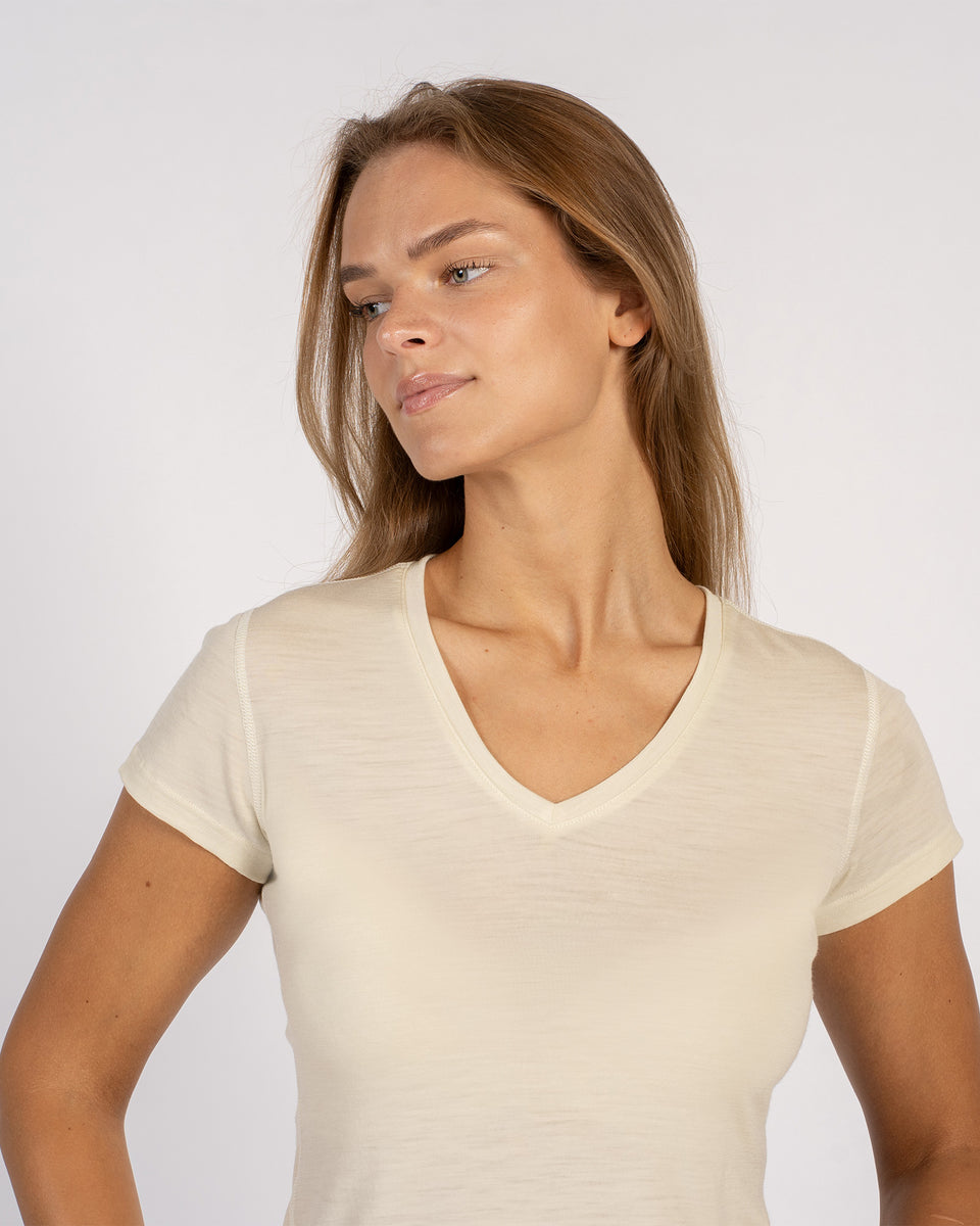 Close-up van een vrouw in een licht natuurlijk Merinowollen T-shirt met V-hals.
