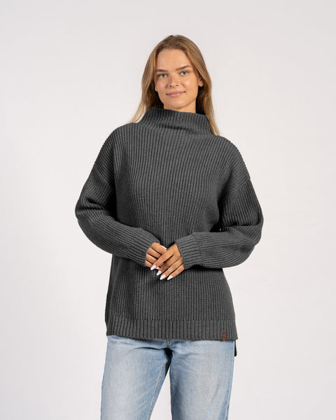 Front view of woman in dark gray knitted merino wool sweater with high collar.