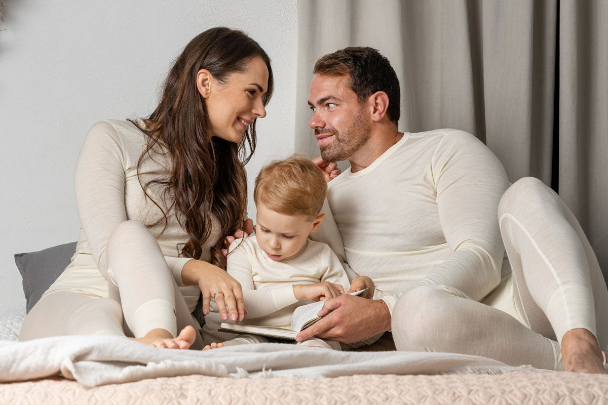 Familie op bed in bijpassende pyjama's van merinowol