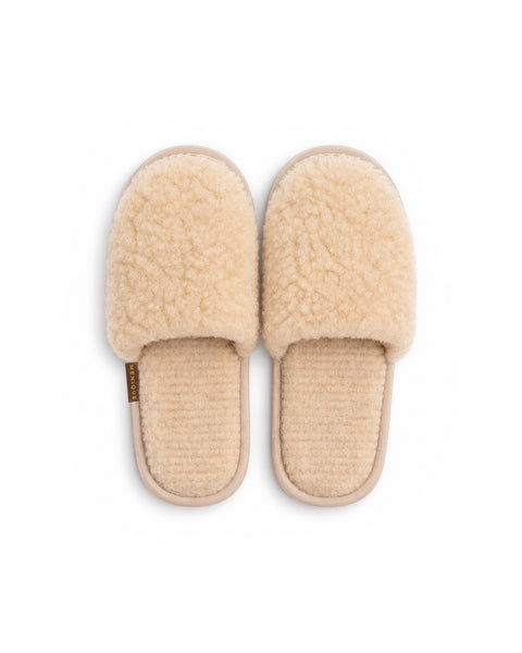 A top-down view of a pair of beige fuzzy slip-on slippers with matching beige insoles and a "MENIQUE" tag on the side of the left slipper.